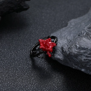 Gothic black thorn branch ring with red flower on dark stone background