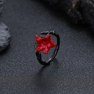 Macro shot of a gothic black thorn ring featuring a vibrant red enamel flower centerpiece