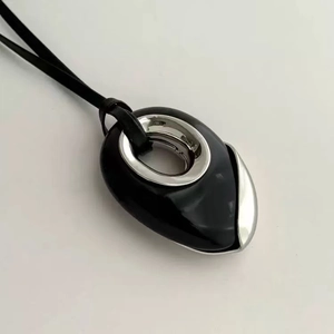 Gros plan du pendentif en onyx noir organique avec anneau en métal sur cordon en cuir