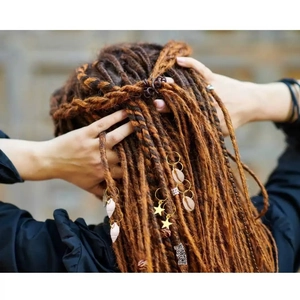 Mix of gold dreadlock rings, shell charms and metal hair tubes on braided hair