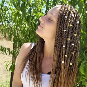 Détail de tresses Senegalese twist avec des bagues de cheveux dorées et argentées