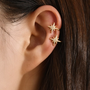 Bagues d'oreille dorées en forme d'étoile avec zircons brillants portées sur le cartilage
