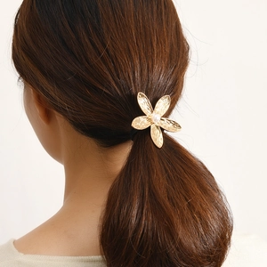 Minimalist gold flower hair tie with pearl center and textured metal petals