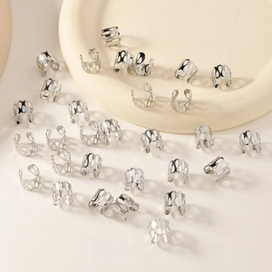 Close-up of silver hollow metal dreadlock rings on a minimalist beige tray