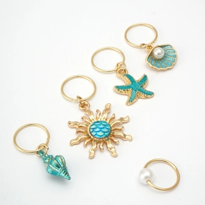 Detailed close-up of 5 gold-plated ocean-themed hair rings with starfish and shells