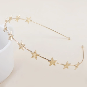 Detailed close-up of a golden headband featuring textured metallic stars on white ceramic