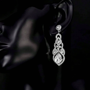 Exaggerated silver tassel drop earrings with sparkling pear-cut crystals on a model