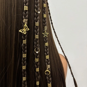 Vue détaillée d'anneaux de tresses dorés avec pendentifs en perle, étoile et papillon