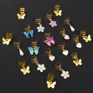 Gold spiral hair rings set with butterfly, flower and pearl charms on dark background