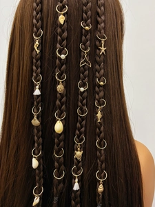 Détails de breloques marines dorées et perles sur des tresses de cheveux longs