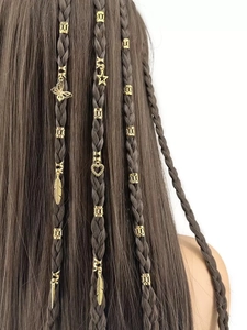 Dettaglio macro di anelli per capelli dorati con ciondoli a farfalla e stella su trecce