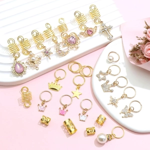 Dettaglio di gioielli per capelli dorati con strass rosa, perle e ciondoli corona