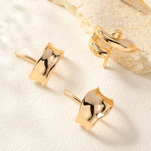 Macro shot of minimalist gold curved alloy hair hooks on textured stone background