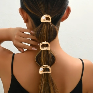Close-up of three gold hollow hair clips with pearls used on a ponytail hairstyle