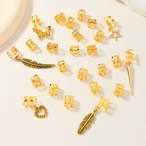 Set of 26 gold leaf dreadlock hair rings with butterfly and star charms on beige background
