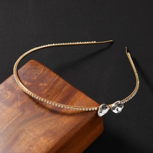 Serre-tête doré élégant avec strass et motif nœud en cristal sur fond noir profond