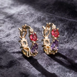 Elegant gold-plated huggie earrings with colorful zirconia stones on dark velvet background