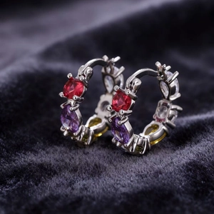 Silver hoop earrings with red purple yellow and clear zircon stones on velvet