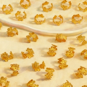 Golden flower adjustable rings set with 3D petal design on textured background