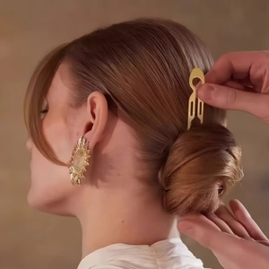 Detailed view of elegant U-shaped hair pin and gold sunflower earrings on a woman