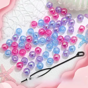 Gros plan de perles à cheveux irisées roses, bleues et violettes avec enfileur noir