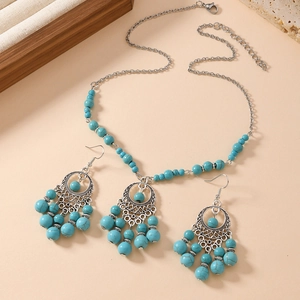 Parure de bijoux bohèmes avec perles turquoise et pompons en métal ethniques sur fond naturel