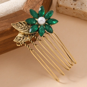 Vintage goldener Haarkamm mit smaragdgrünen Kristallen und Perle auf neutralem Grund