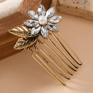 Vintage-Haarkamm in Gold mit Kristallblume und Perle auf einem eleganten warmen Hintergrund
