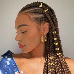 Detailed view of golden butterfly and hollow metal rings on braided hair extensions