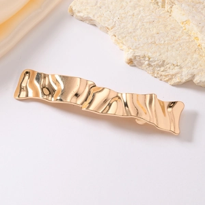 Pince à cheveux dorée ondulée en métal poli avec texture irrégulière au style minimaliste