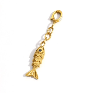 Detailed macro view of a 18K gold fish pendant with blue gemstone eye and scale texture