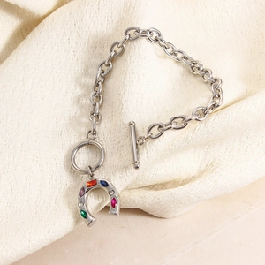 Detail of silver chain bracelet with colored zircon horseshoe charm and OT buckle closure
