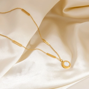 Detail of 18K gold necklace featuring Roman numerals pendant on soft silk fabric