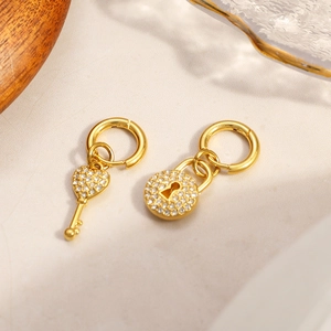 Boucles d'oreilles asymétriques en acier doré avec pendentifs clé et cadenas sertis de zircons