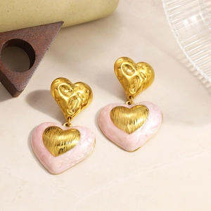 Détail de boucles d'oreilles pendantes cœur vintage dorées avec texture marbrée rose