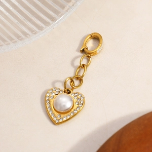 Detailed macro view of a gold heart charm with pearl and crystals on textured stone