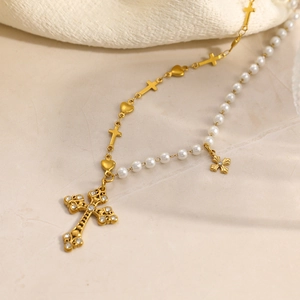 Elegant gold cross pearl necklace with heart pendant on a soft textured background