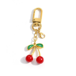 Detail of red cherry pendant keychain with golden swivel hook and green enamel leaves