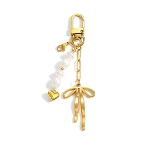 Golden keychain with bow pendant, heart charm and faux pearls on white background
