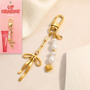 Detail of 18K gold-plated bow and heart pendant with pearls on a branded display card