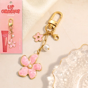 Pink enamel flower and daisy gold charm keychain with pearl detail on display card