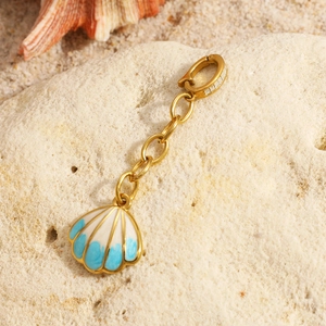 18K gold plated stainless steel shell pendant necklace with blue enamel on a sandy rock
