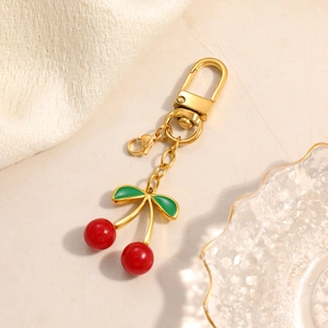 Close-up of 18K gold-plated cherry pendant with red beads and green enamel leaves