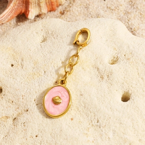 Detailed macro of gold shell pendant with pink enamel on a sandy beach background