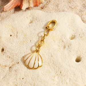 Detail of a 18K gold-plated shell pendant with a spring clasp on a sandy beach setting