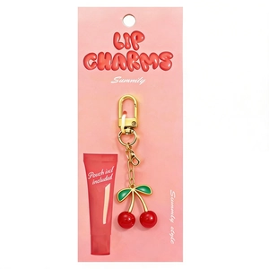 Detail showing cherry lip charm with gold keychain on pink product packaging card