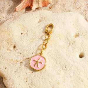 Detail of pink enamel starfish pendant with 18K gold plating on a beach rock