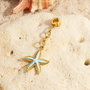 Golden starfish charm with light blue enamel and 18K gold plating on beach sand
