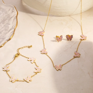 Detail von 18K vergoldetem Schmetterling-Schmuckset mit rosa Anhängern auf Stein