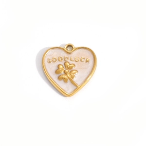 Macro detail of heart charm with clover relief and Good Luck engraving in gold and enamel
